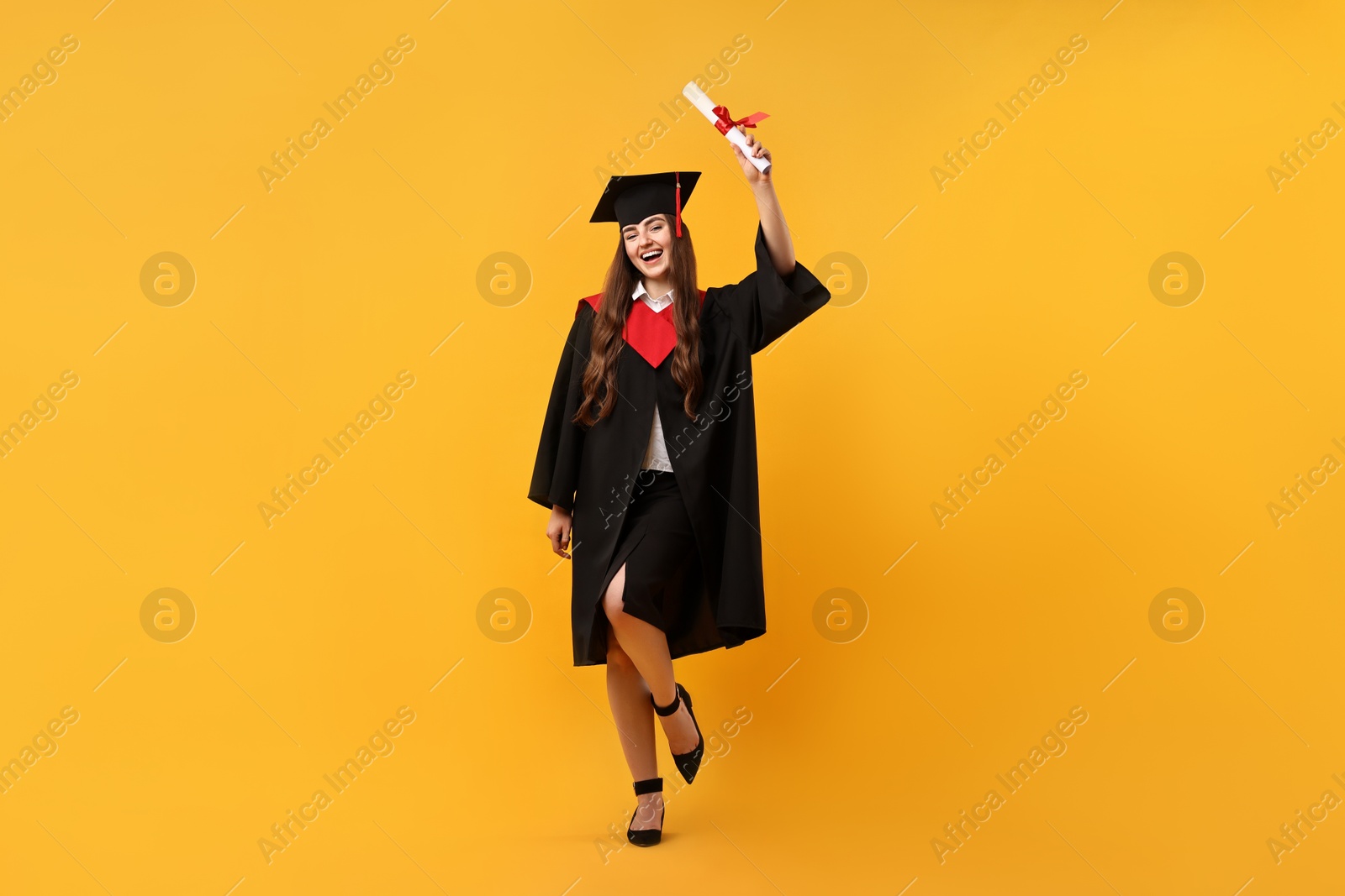 Photo of Happy student with diploma after graduation on orange background