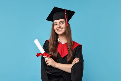 Photo of Happy student with diploma after graduation on light blue background