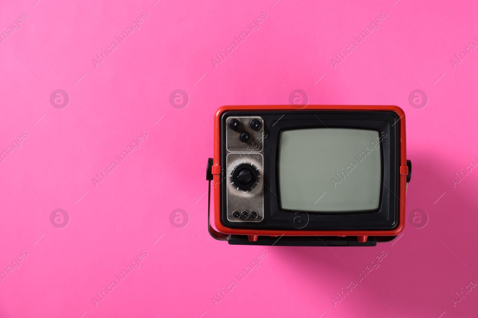 Photo of Retro tv set on pink background, top view. Space for text