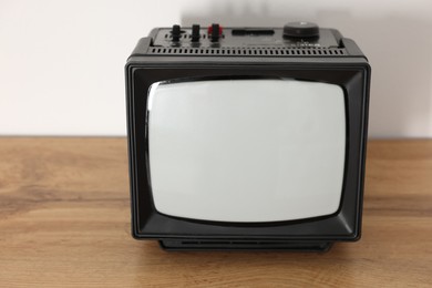 Photo of Retro tv set on wooden shelf against white wall