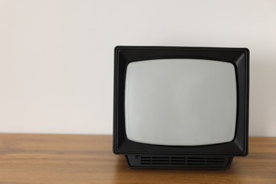 Photo of Retro tv set on wooden shelf against white wall. Space for text