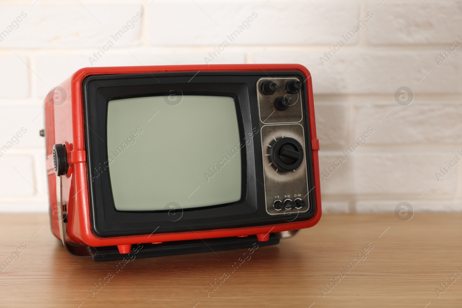 Photo of Retro tv set on wooden shelf against white brick wall