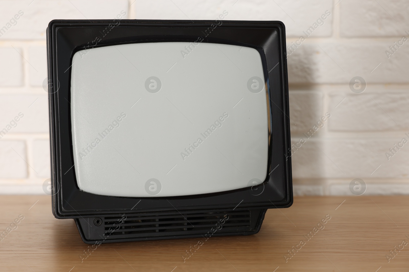 Photo of Retro tv set on wooden shelf against white brick wall