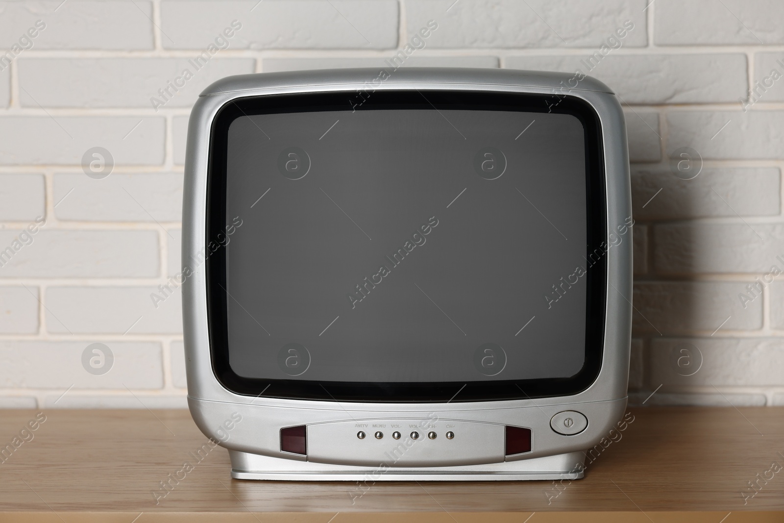 Photo of Retro tv set on wooden shelf against white brick wall