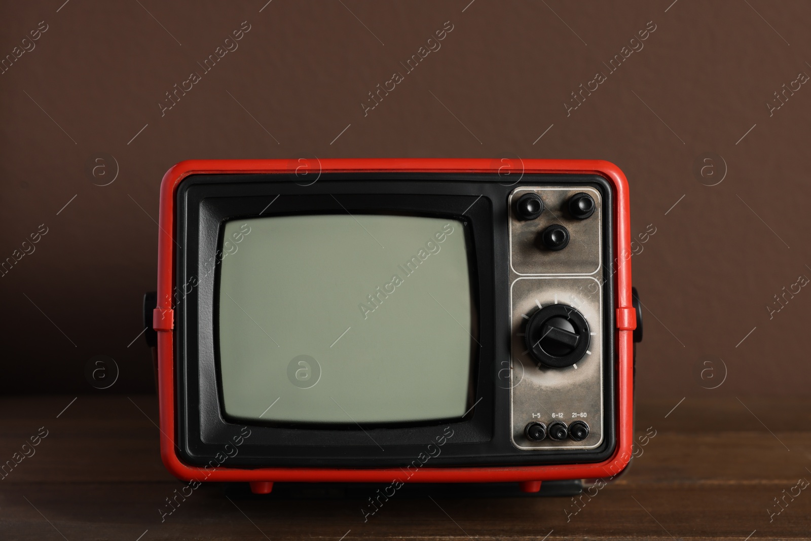 Photo of Retro tv set on wooden shelf against brown wall