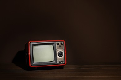 Photo of Retro tv set on wooden shelf against dark background. Space for text