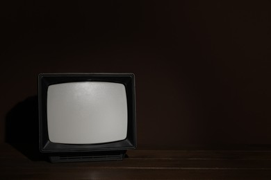 Photo of Retro tv set on wooden shelf against dark background. Space for text