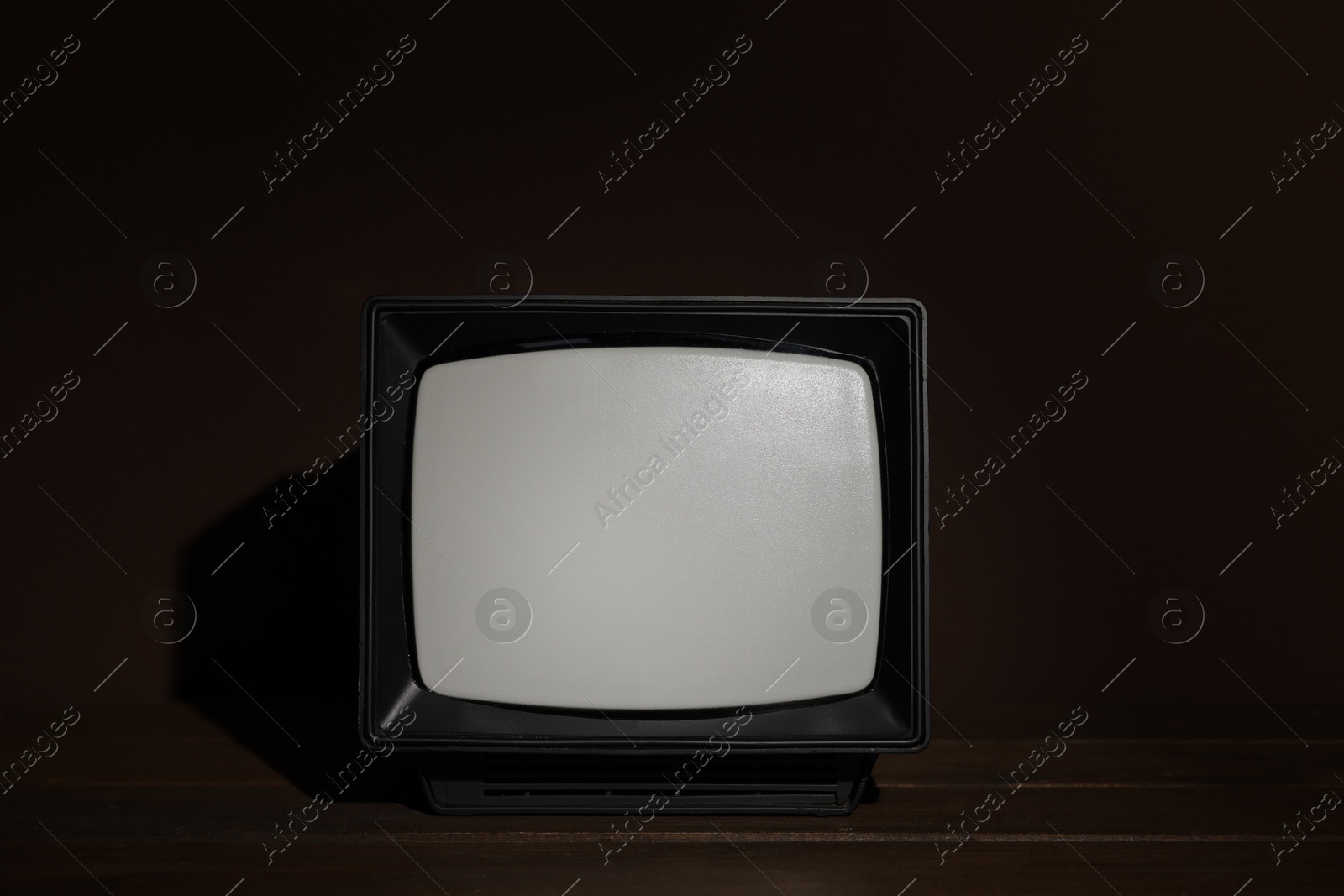 Photo of Retro tv set on wooden shelf against dark background