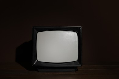 Retro tv set on wooden shelf against dark background