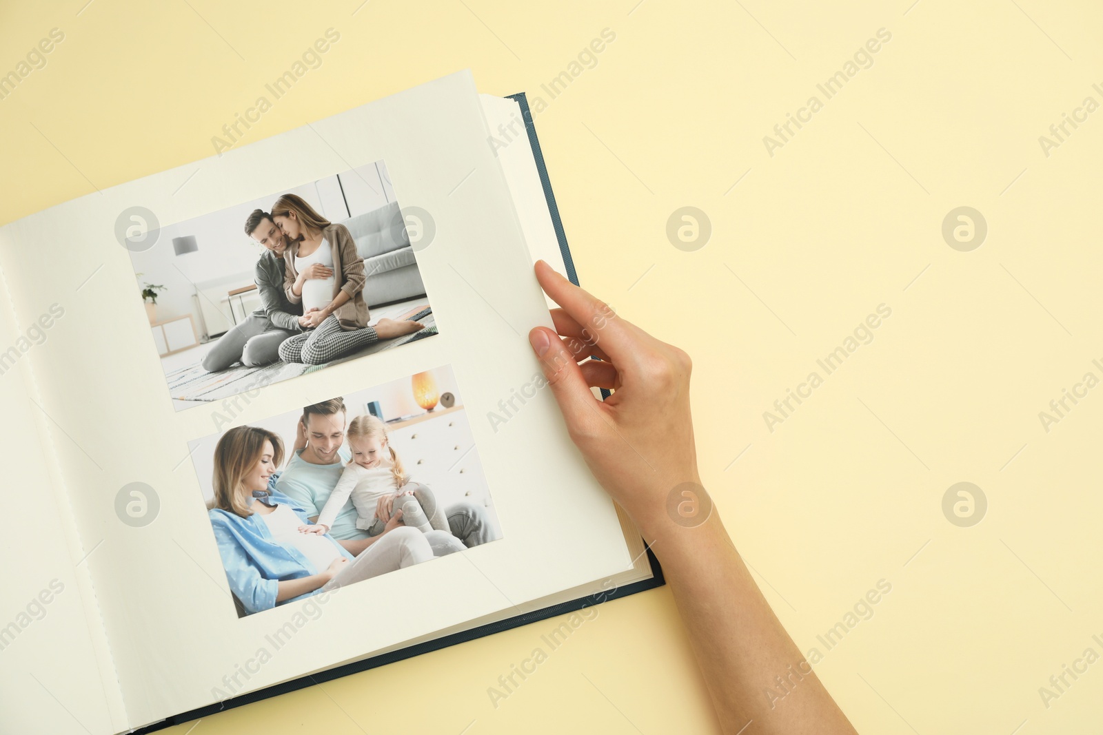 Photo of Woman looking at family photos in photo album on beige background, top view. Space for text