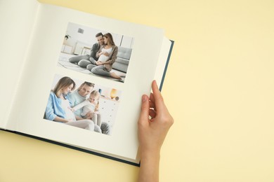 Photo of Woman looking at family photos in photo album on beige background, top view. Space for text