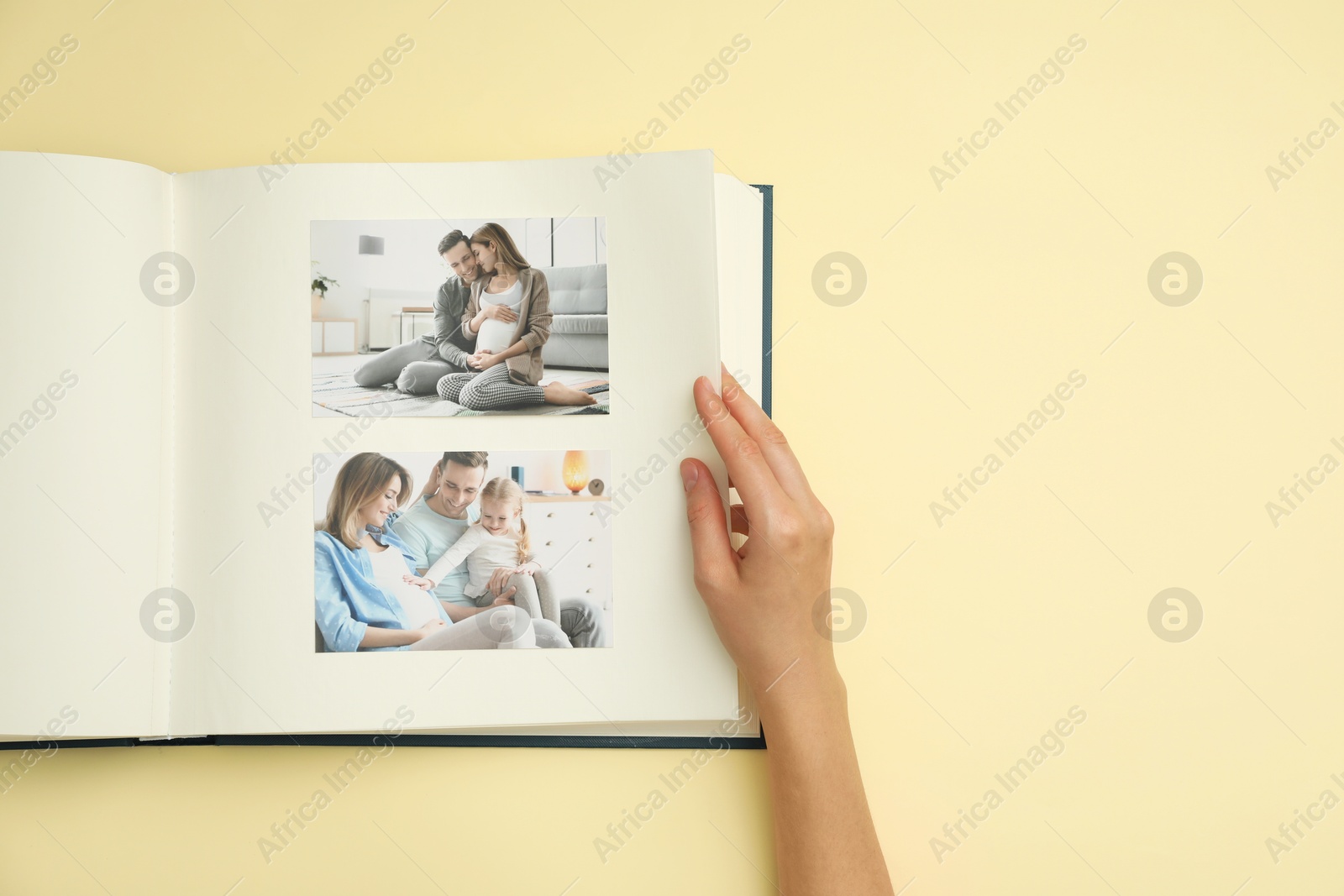 Photo of Woman looking at family photos in photo album on beige background, top view. Space for text