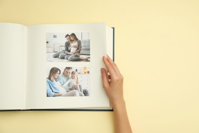 Photo of Woman looking at family photos in photo album on beige background, top view. Space for text