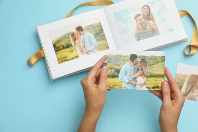 Photo of Woman with open photo album and different photos on light blue background, top view