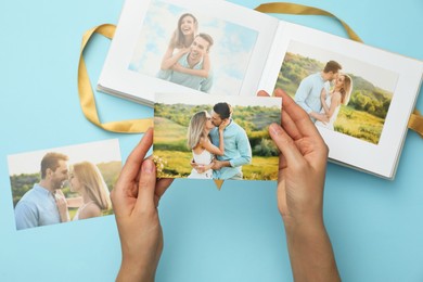 Photo of Woman with open photo album and different photos on light blue background, top view