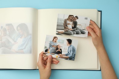 Woman with open photo album and different photos on light blue background, top view