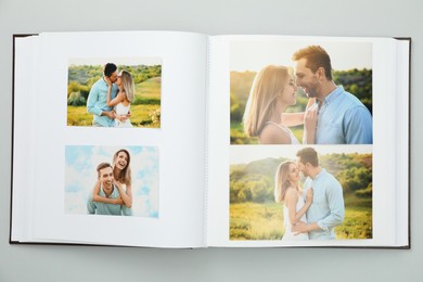 Photo of Open photo album with different photos on grey background, top view