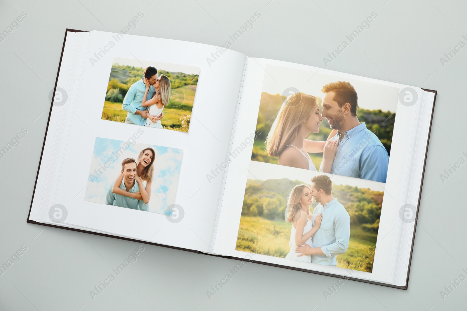 Photo of Open photo album with different photos on grey background, top view