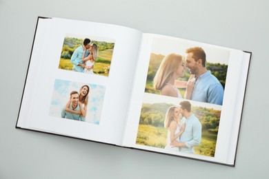 Photo of Open photo album with different photos on grey background, top view