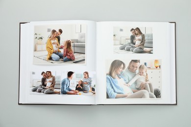 Photo of Open photo album with different photos on grey background, top view