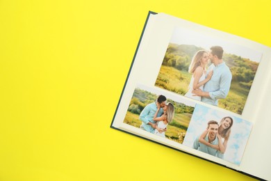 Open photo album with different photos on yellow background, top view. Space for text