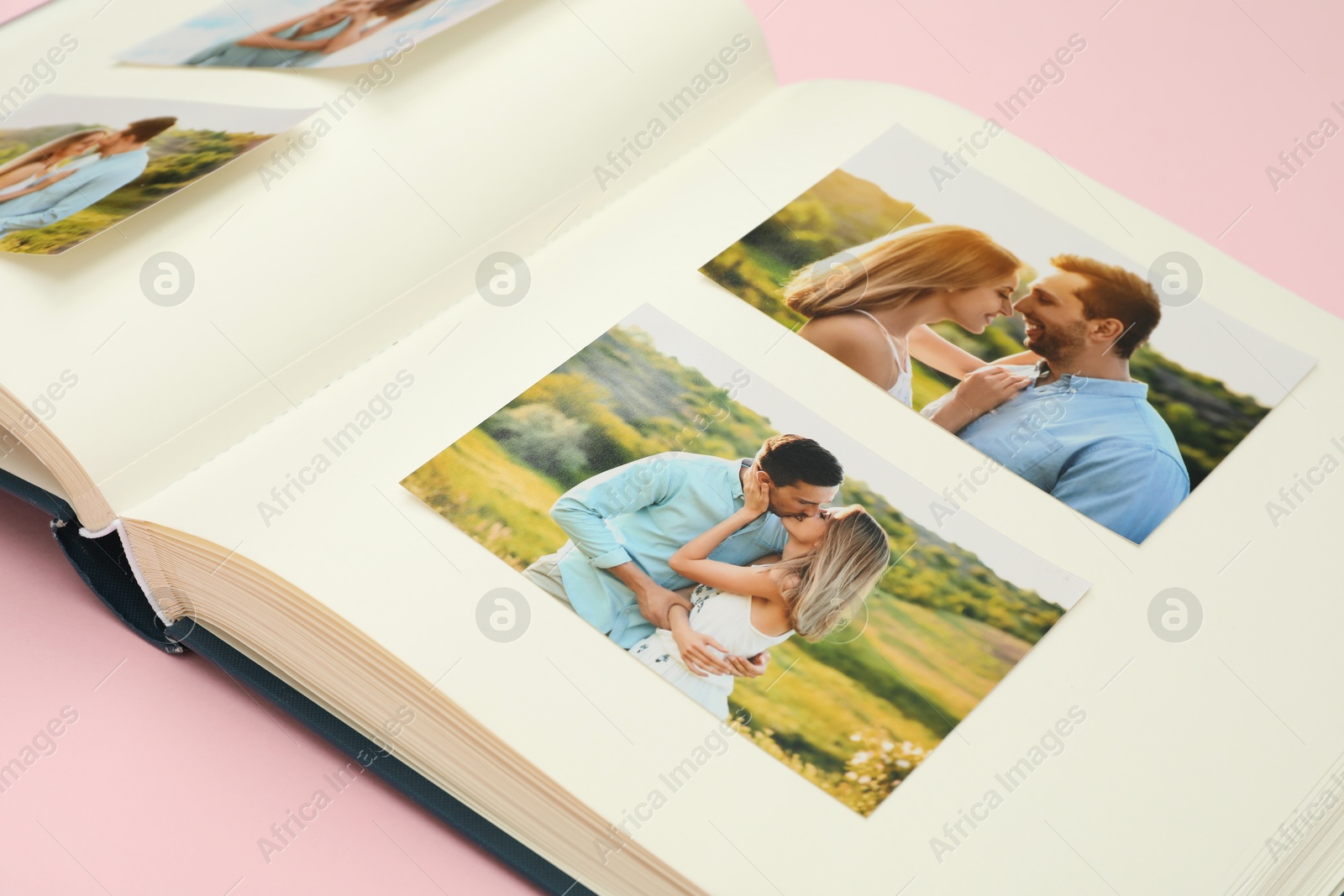 Photo of Open photo album with different photos on pink background, closeup