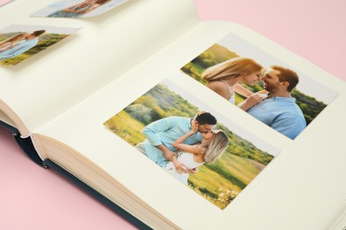 Open photo album with different photos on pink background, closeup