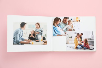 Photo of Open photo album with different photos on pink background, top view