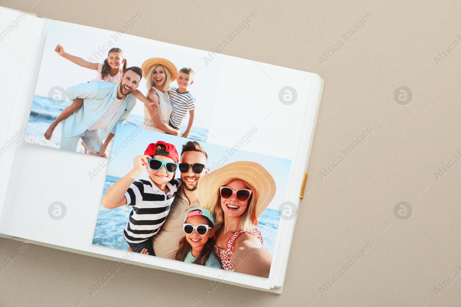 Photo of Open photo album with different photos on beige background, top view