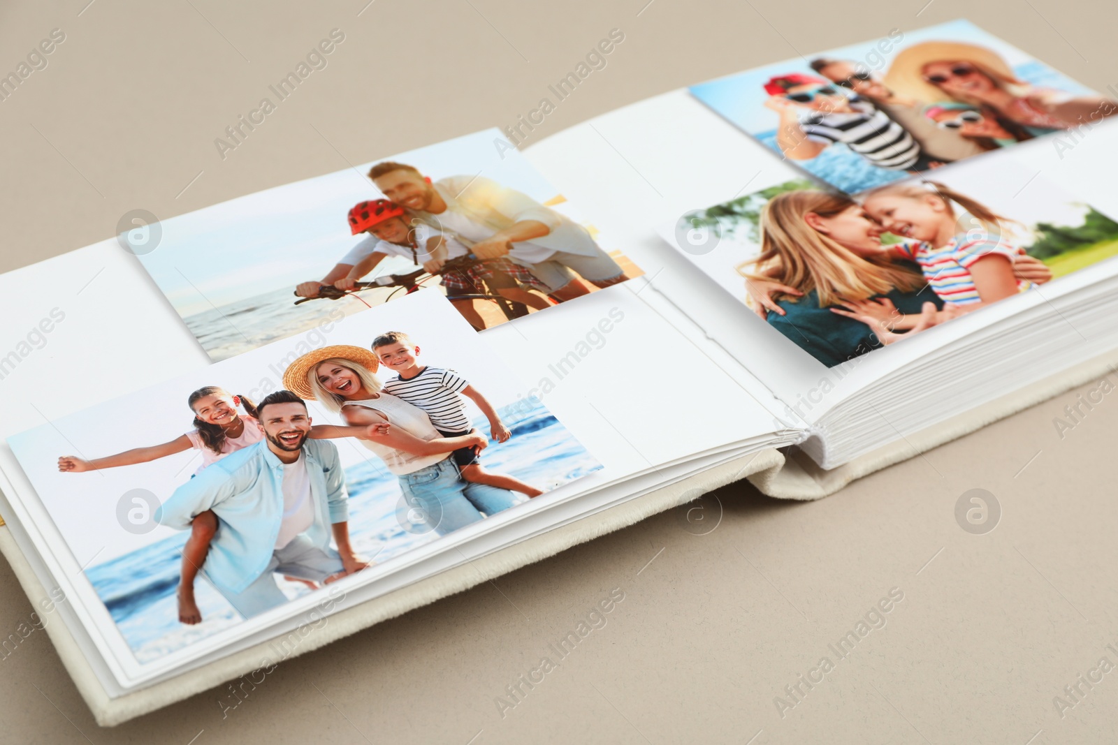 Photo of Open photo album with different photos on beige background, closeup