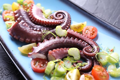 Tasty boiled octopus tentacles and salad on grey textured table, closeup