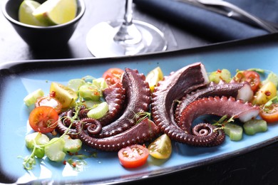 Photo of Tasty boiled octopus tentacles and salad on grey table, closeup