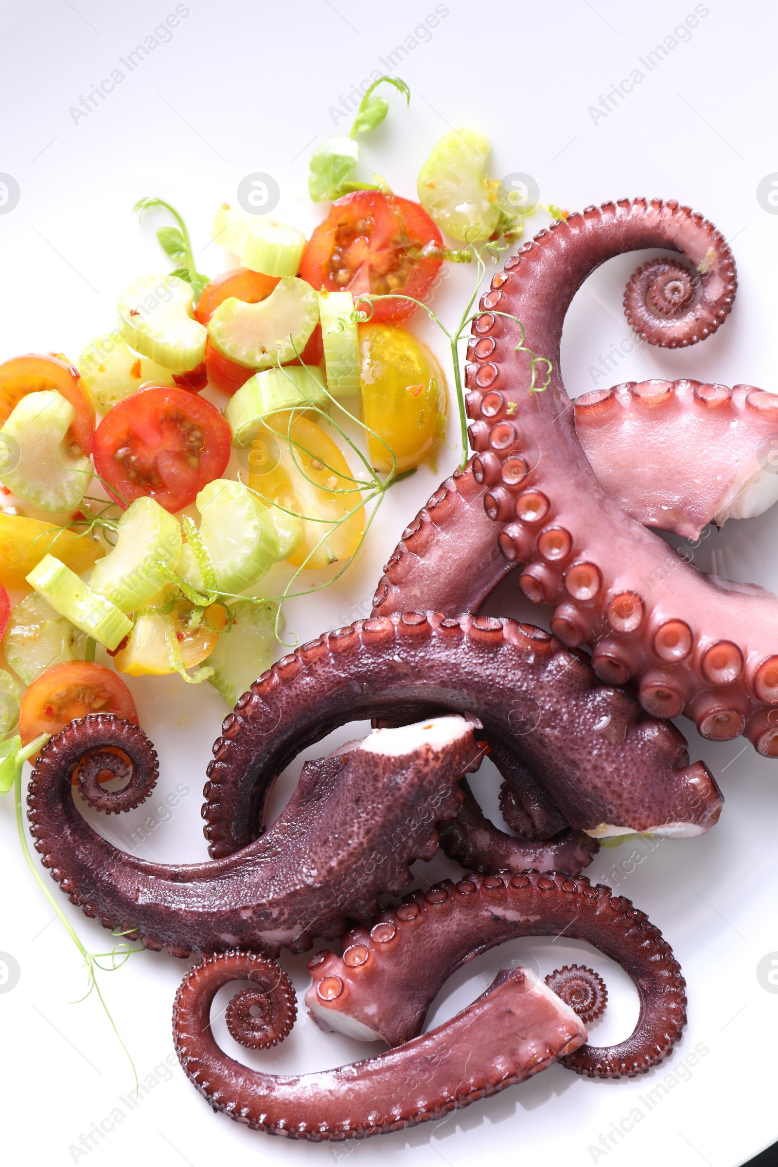 Photo of Tasty boiled octopus tentacles and salad on plate, above view