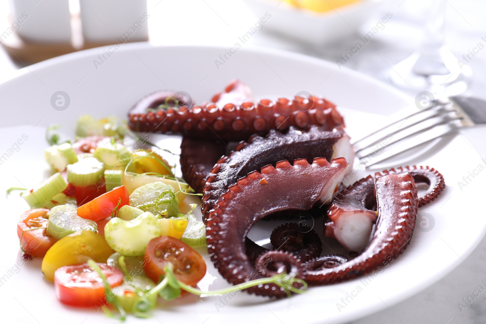 Photo of Plate with tasty boiled octopus tentacles and salad on table, closeup