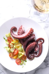 Plate with tasty boiled octopus tentacles and salad on white marble table, top view