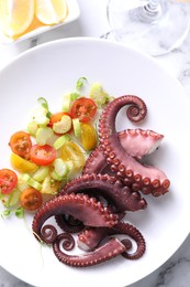 Photo of Plate with tasty boiled octopus tentacles and salad on white marble table, top view