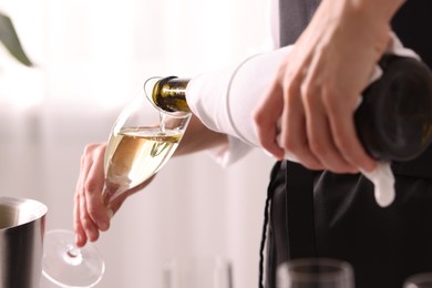 Photo of Waiter pouring champagne into glass indoors, closeup