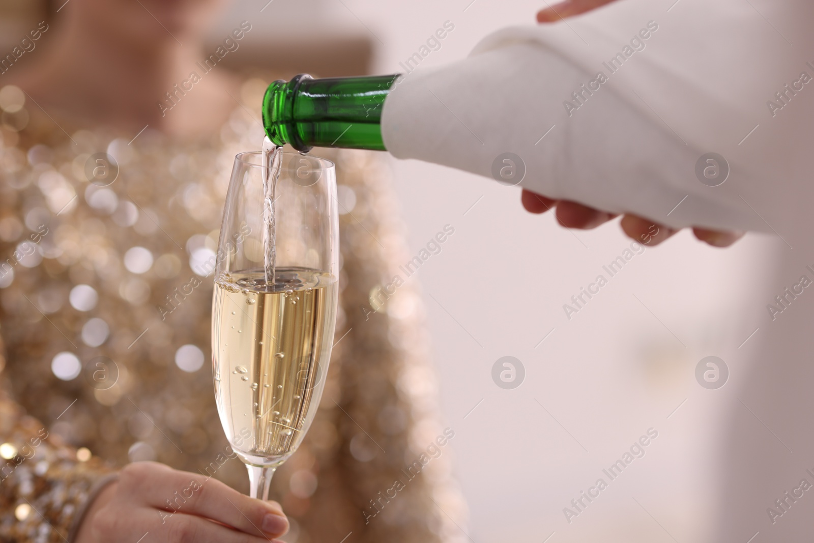 Photo of Waiter pouring champagne into woman's glass, closeup