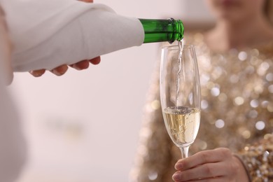 Photo of Waiter pouring champagne into woman's glass, closeup