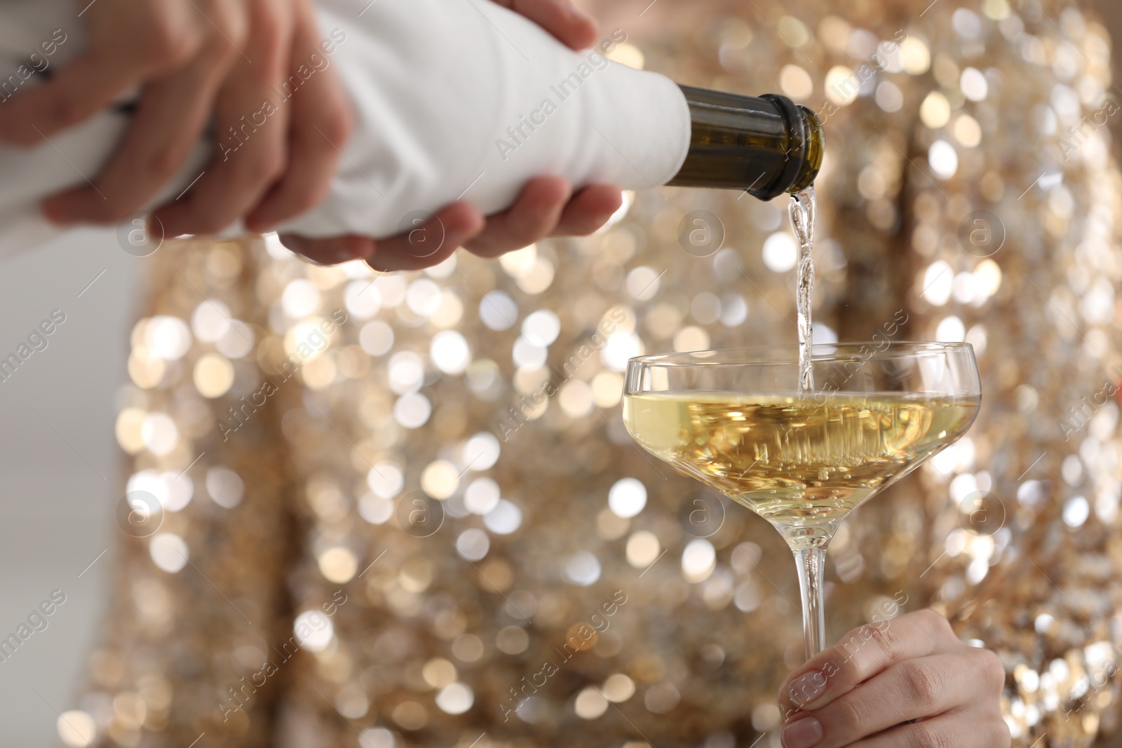 Photo of Waiter pouring champagne into woman's glass, closeup