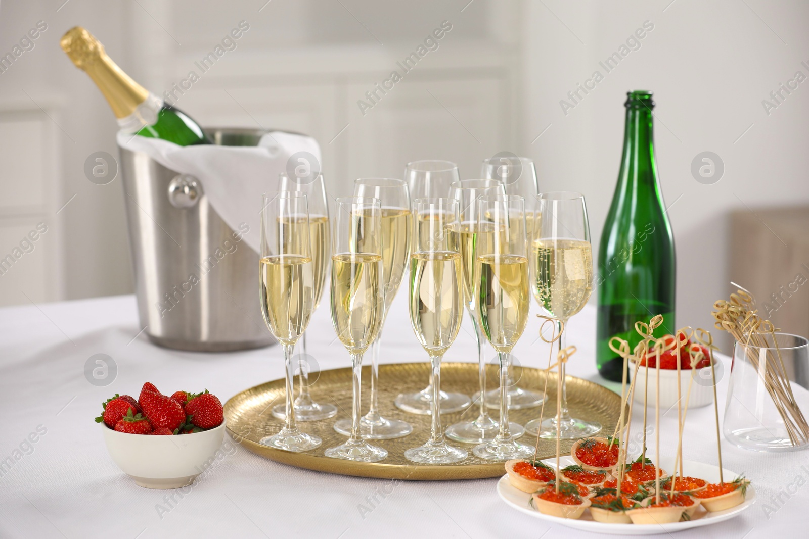 Photo of Champagne, strawberries and canapes with red caviar on white table