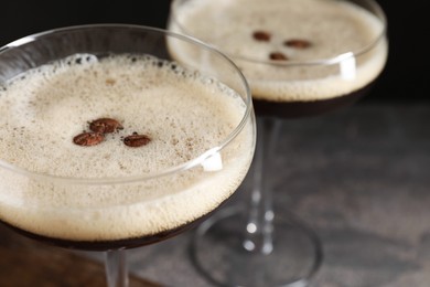 Photo of Glasses of delicious espresso martini and coffee beans on table, closeup