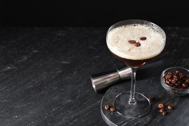 Photo of Glasses of delicious espresso martini, jigger and coffee beans on dark textured table, closeup. Space for text