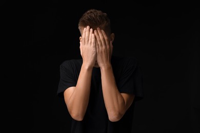 Photo of Portrait of scared young man on black background