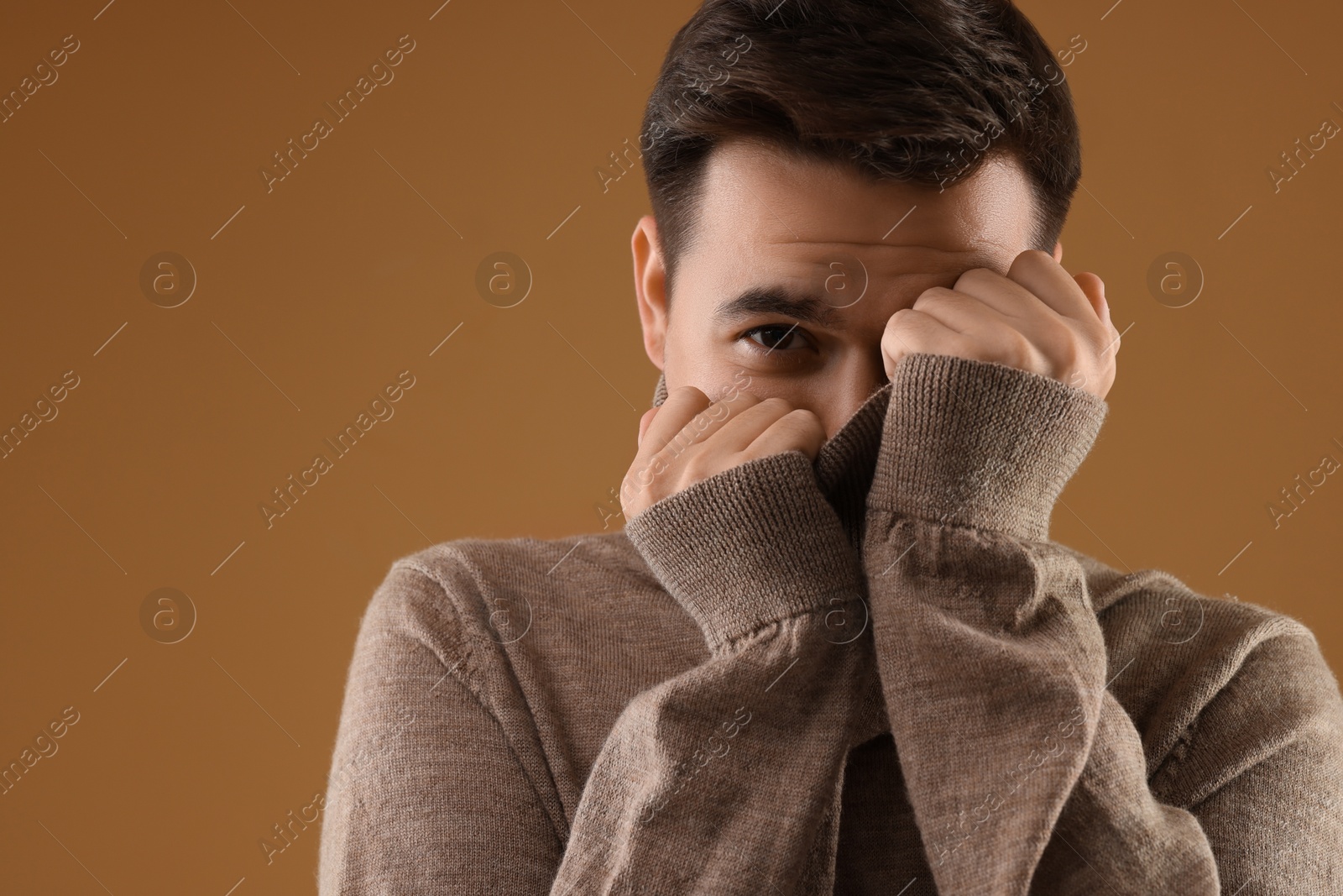 Photo of Portrait of scared young man on brown background, space for text