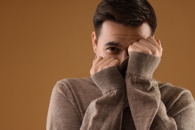 Photo of Portrait of scared young man on brown background, space for text