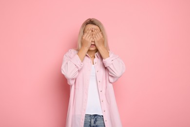 Portrait of scared woman on pink background