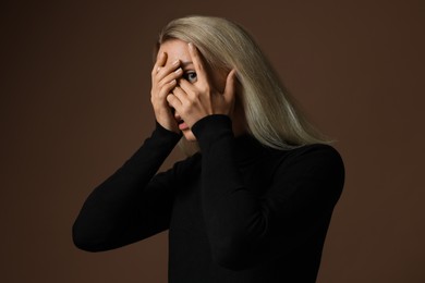 Portrait of scared woman on brown background