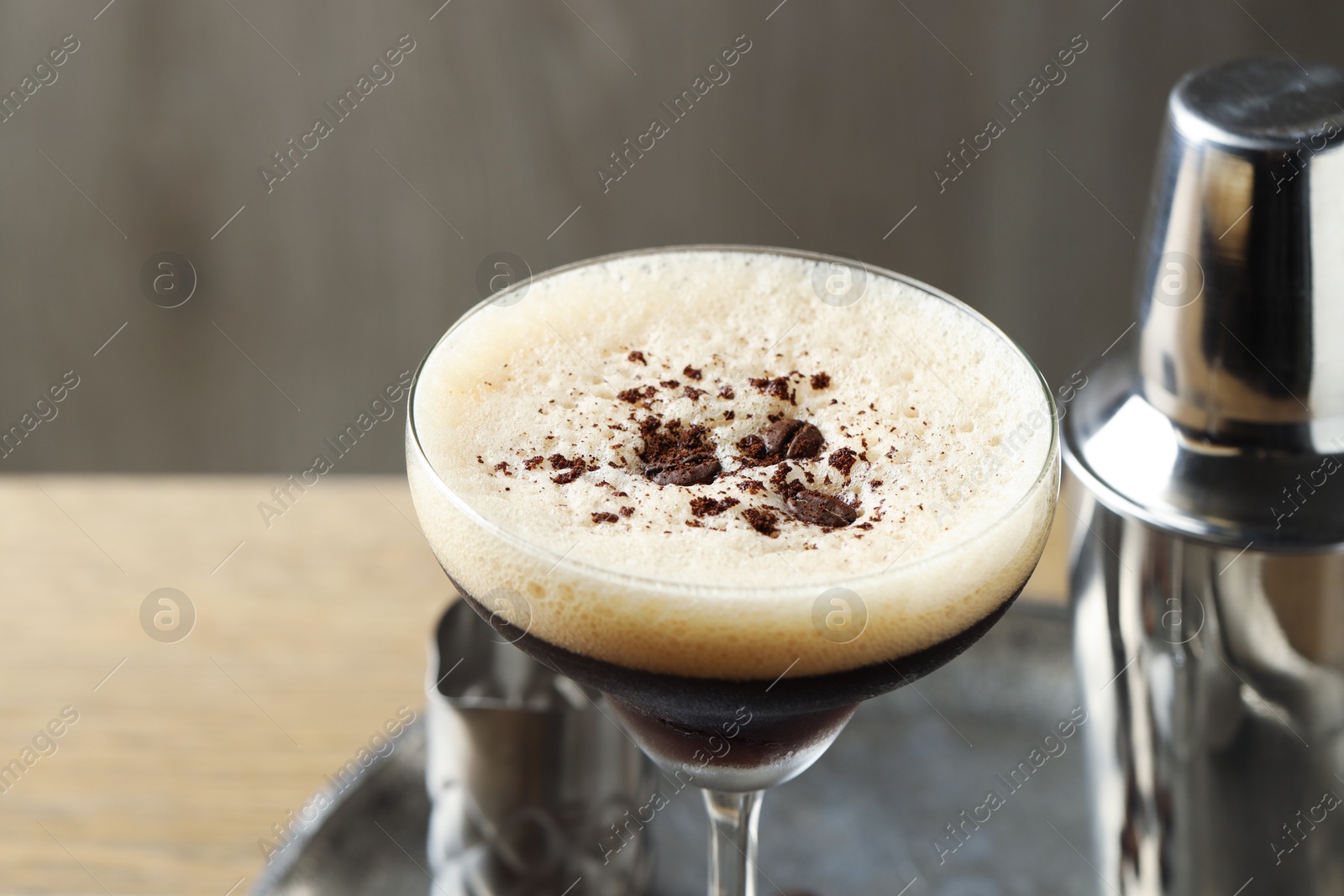 Photo of Tray with delicious espresso martini in glass and shaker on table, closeup