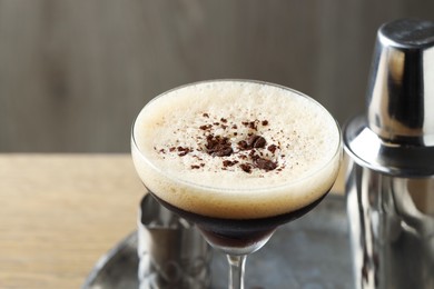 Photo of Tray with delicious espresso martini in glass and shaker on table, closeup